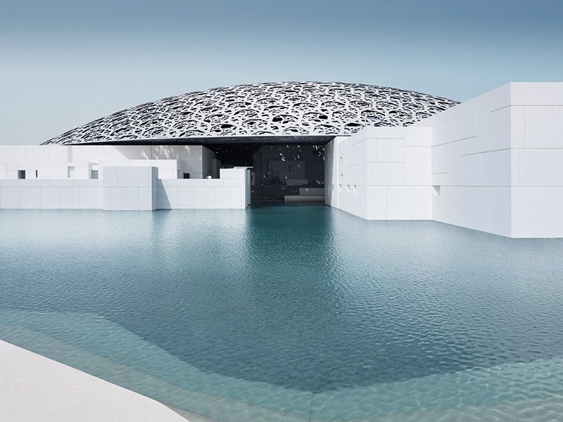 The dome atop the Louvre in Abu Dhabi is constructed from layered aluminum and stainless-steel honeycomb shapes that filter the sunlight into patterned shards that hit the white granite on the walls and floor of the cube-shaped museum buildings. Photograph: ©Louvre Abu Dhabi/Mohamed Somji