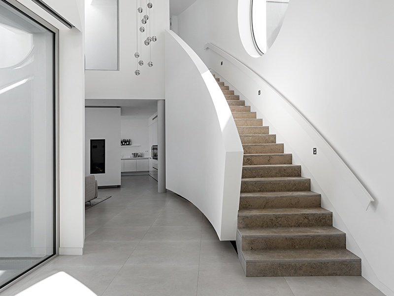 Further highlights of Elliptical House in Luz, Portugal, include minimalist interiors and a marble staircase that follows the curve of the building. 