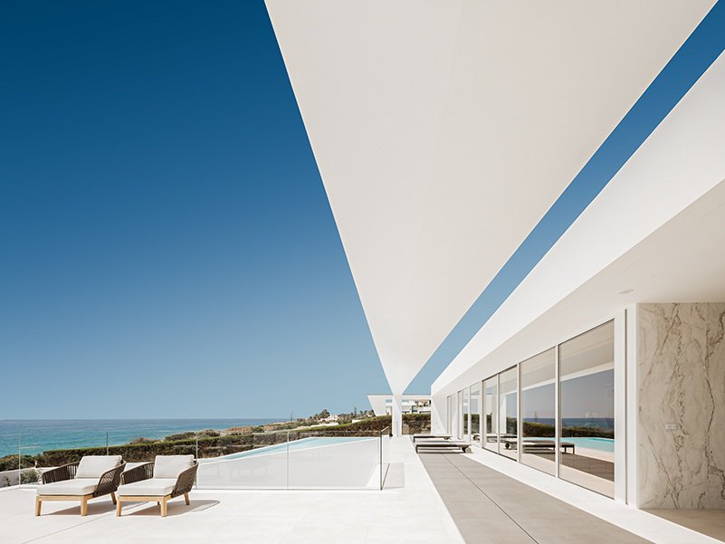 Villa Escarpa’s poolside area is an oasis of white overlooking the Luz coastline in Portugal. 
