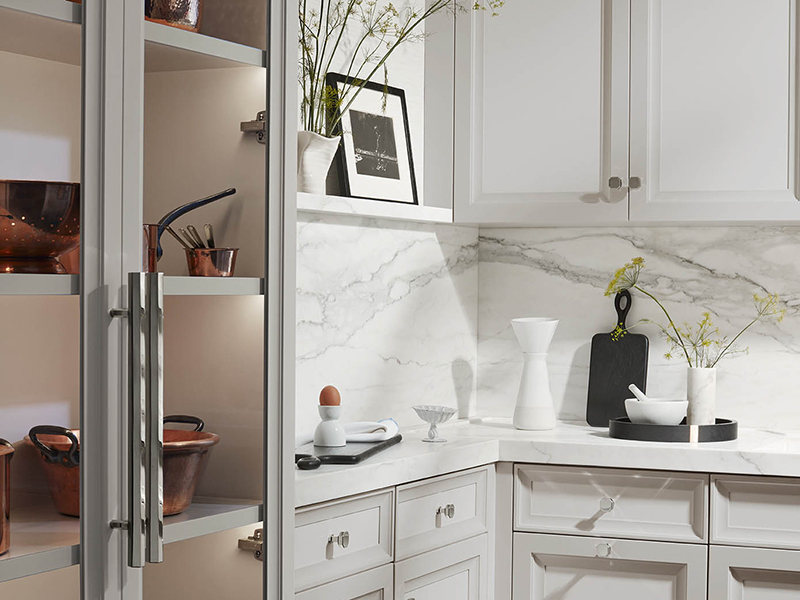 Copper cooking ware is displayed in a white marble kitchen