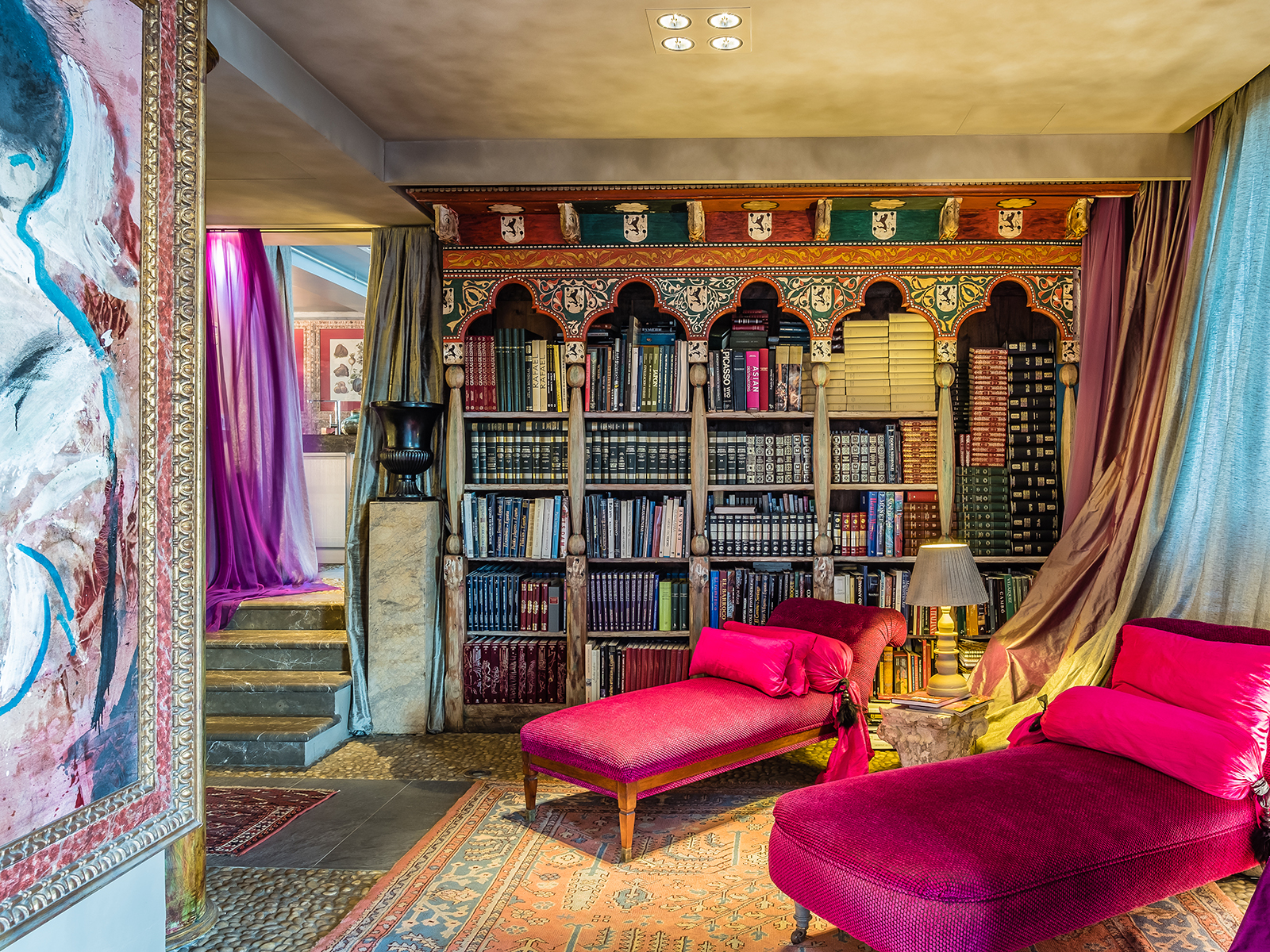 A home library with art and velvet chaise lounges