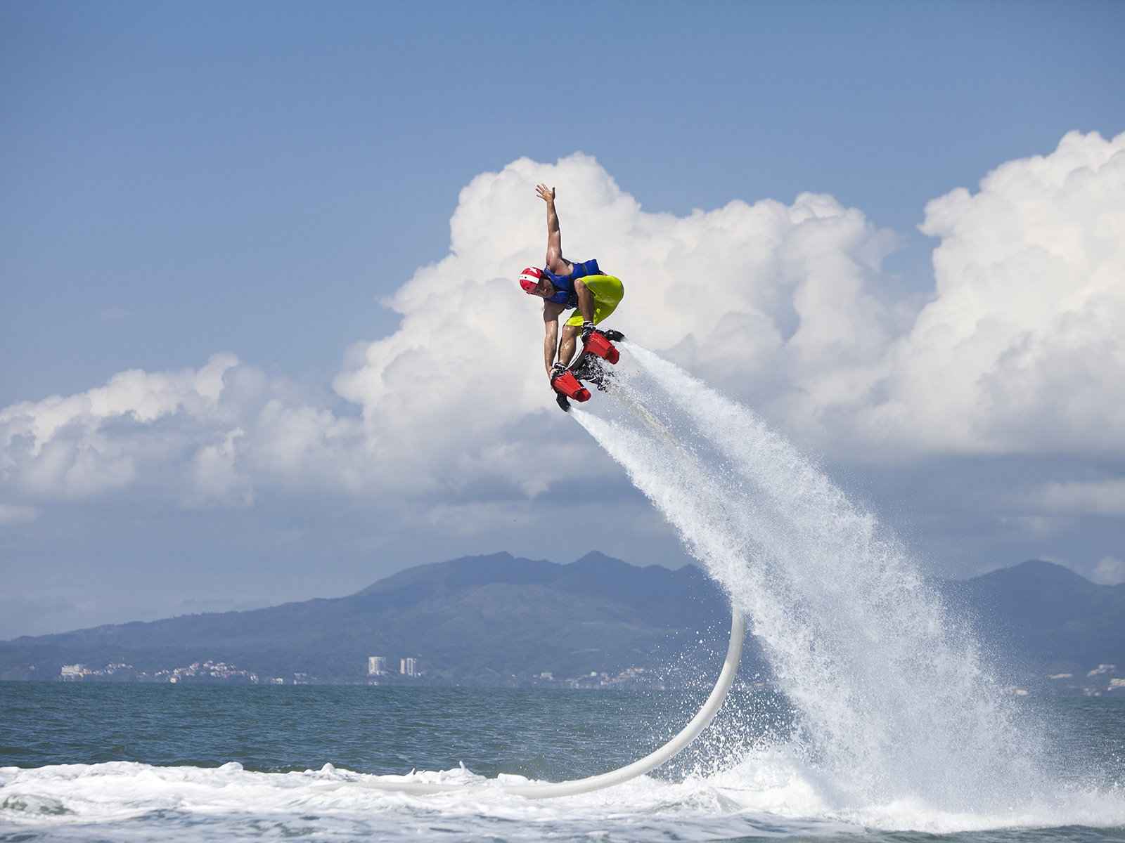 A man is propelled high above the sea by two large water jets