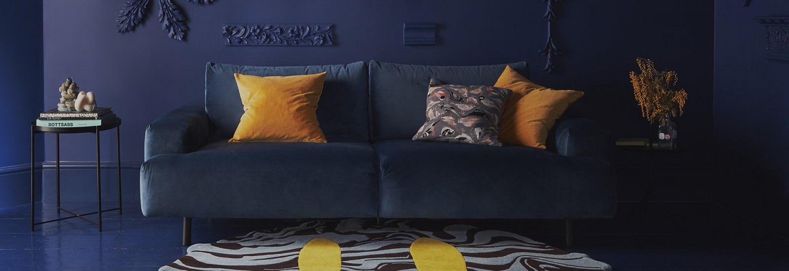 Room with dark blue walls and sofa featuring a large rug with yellow smiley face
