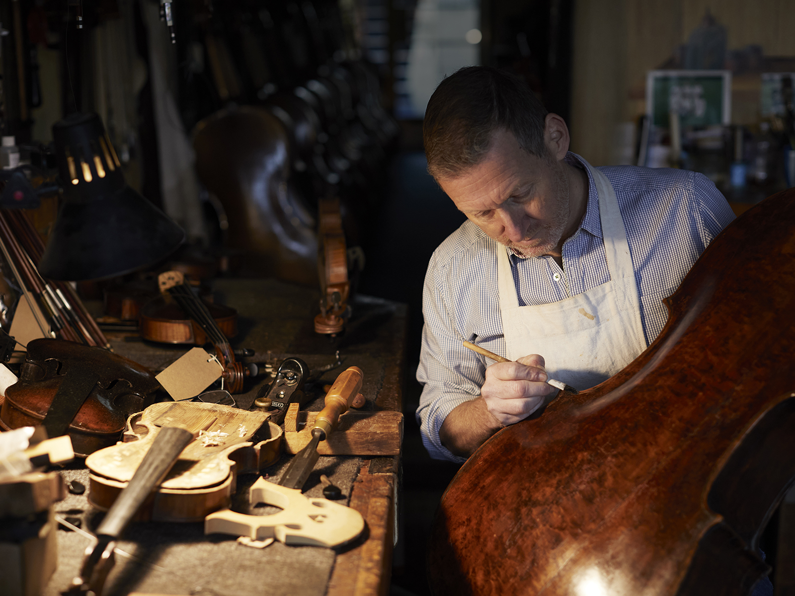 Violin maker Russell Stowe works on a cello by lamplight