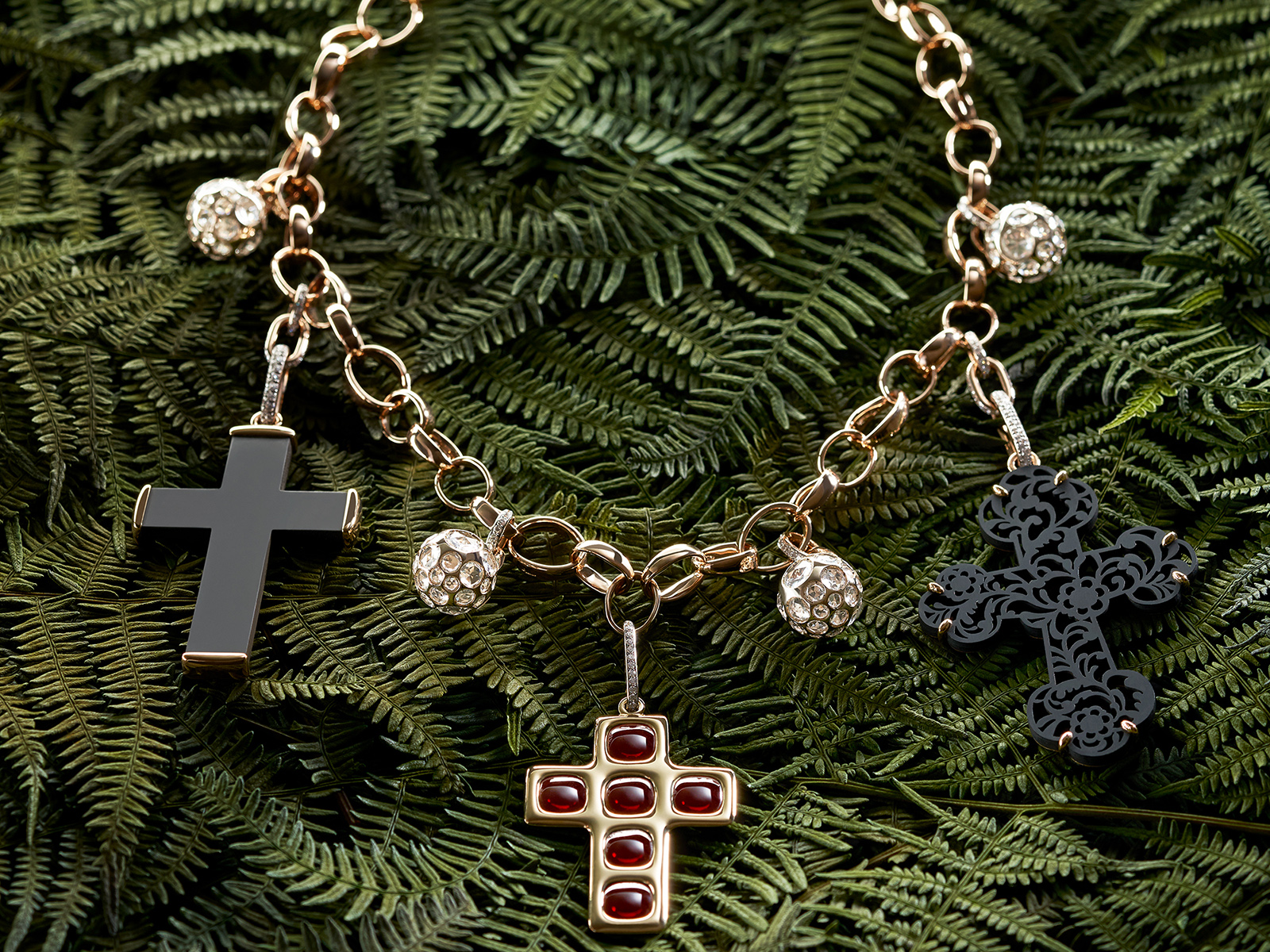 Necklace featuring three crosses against green fern background