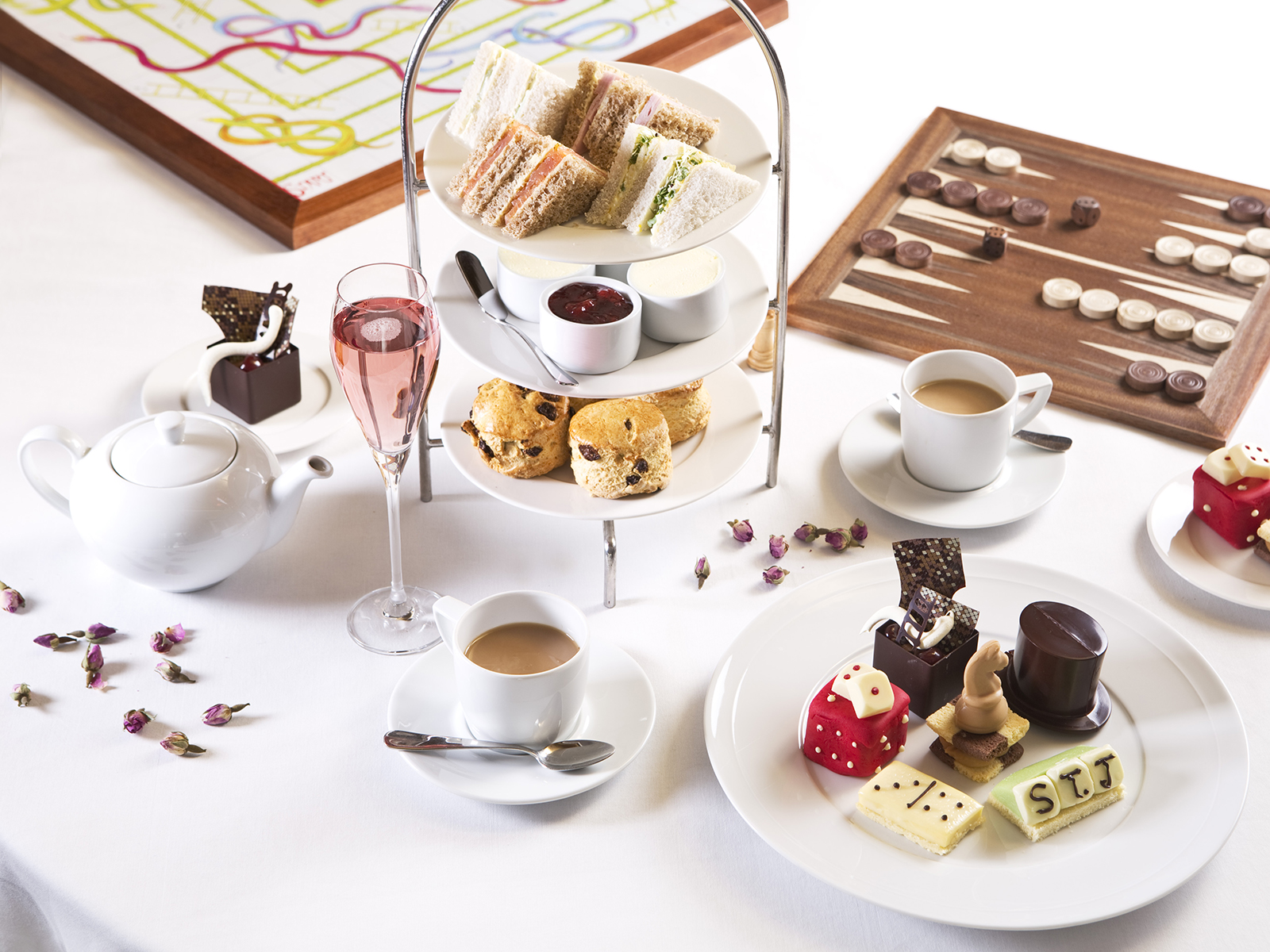 A close up of an afternoon tea with traditional board games on a white tablecloth