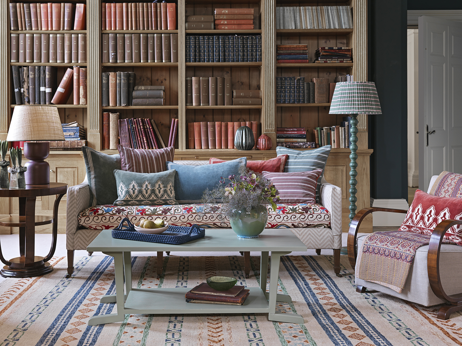 A sofa covered in cushions and a coffee table in front of book cases
