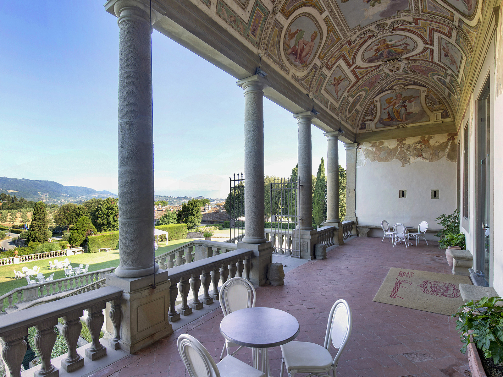 The grand entrance to Tenuta Di Artimino with pillars, a decorated ceiling, and stunning views of the countryside