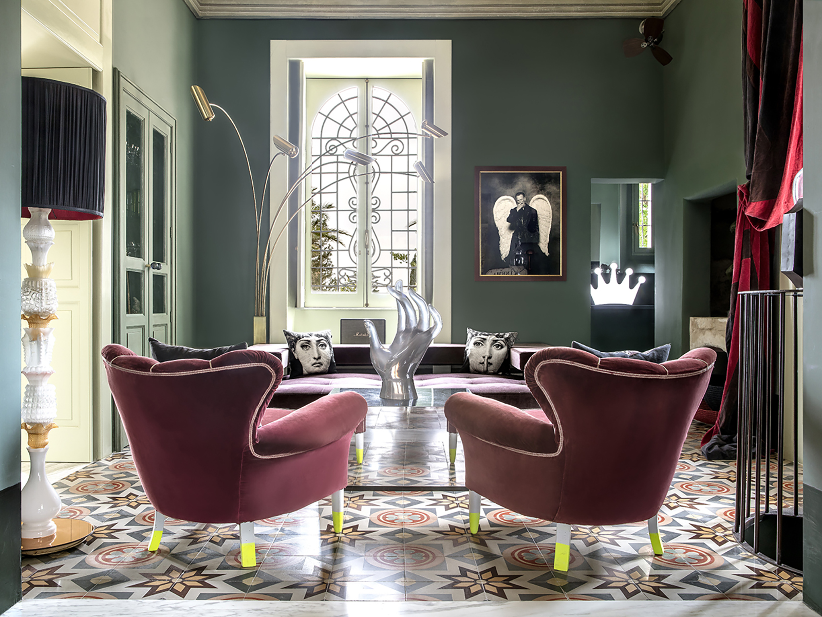 A lounge at Castle Elvira featuring a filed floor, pink velvet chairs, and green walls